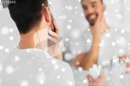 Image of close up of man applying cream to face at bathroom