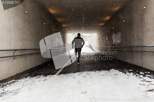 Image of man running along subway tunnel in winter