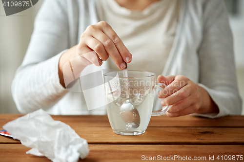 Image of woman stirring medication in cup with spoon