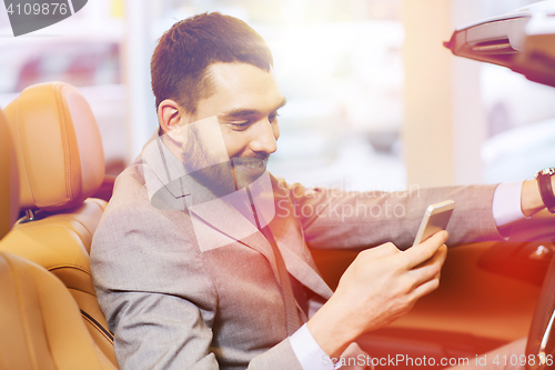 Image of happy man sitting in car at auto show or salon