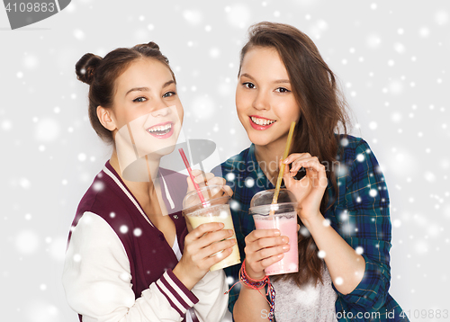 Image of happy pretty teenage girls drinking milk shakes