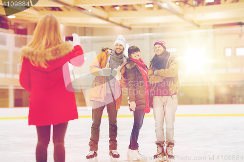 Image of happy friends taking photo on skating rink