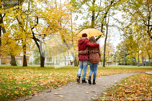 Image of happy couple with umbrella walking in autumn park