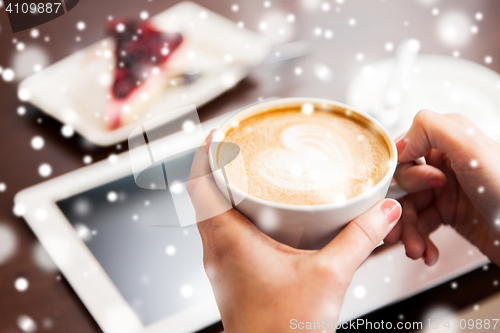 Image of close up of hands with coffee, tablet pc and cake