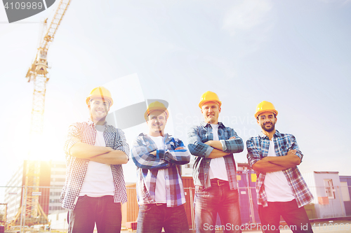 Image of group of smiling builders in hardhats outdoors