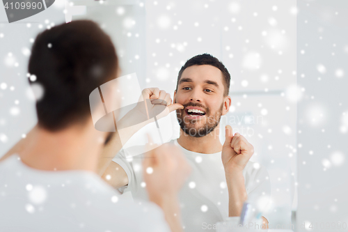 Image of man with dental floss cleaning teeth at bathroom