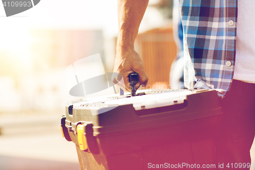 Image of close up of builder carrying toolbox outdoors