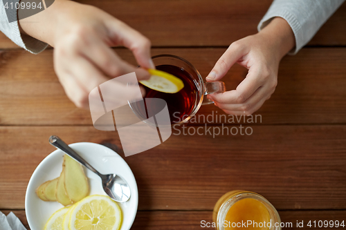 Image of close up of woman adding lemon to tea cup