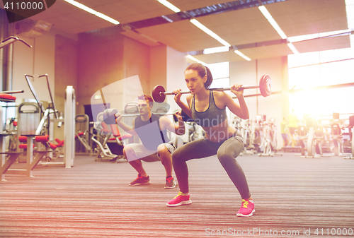 Image of young man and woman training with barbell in gym