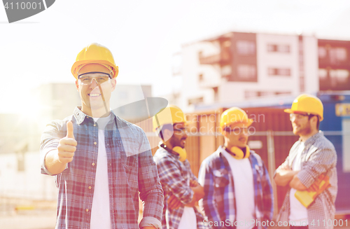 Image of group of smiling builders in hardhats outdoors