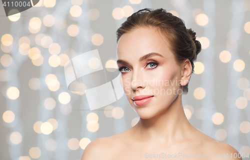 Image of beautiful young woman face over holidays lights