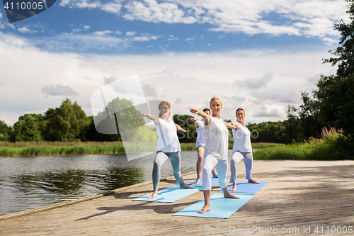 Image of group of people making yoga exercises outdoors