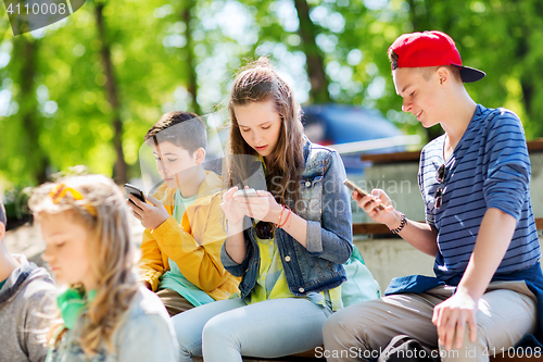 Image of happy teenage friends with smartphones outdoors