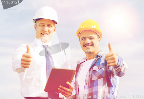 Image of smiling builders in hardhats with tablet pc