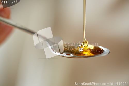 Image of close up of honey pouring to teaspoon