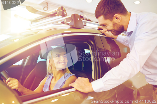 Image of happy couple buying car in auto show or salon