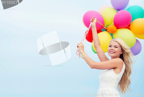 Image of smiling woman with colorful balloons outside