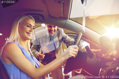 Image of happy woman with car dealer in auto show or salon