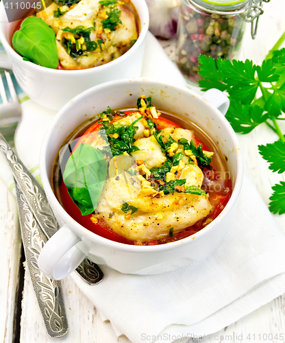 Image of Fish baked with tomato in white bowl on linen napkin