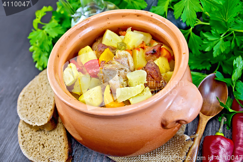 Image of Roast meat and vegetables in clay pot on board
