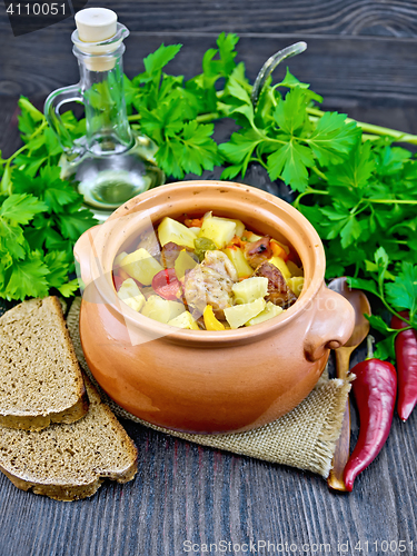 Image of Roast meat and potatoes in clay pot on board