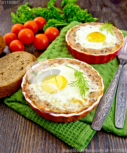 Image of Tartlet meat with egg in pan on dark board