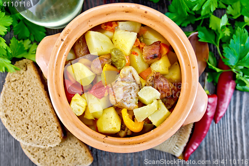 Image of Roast meat and potatoes in clay pot on board top