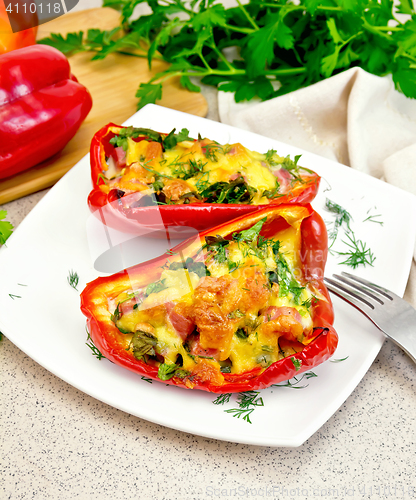 Image of Pepper stuffed with sausage and cheese in white plate on stone t