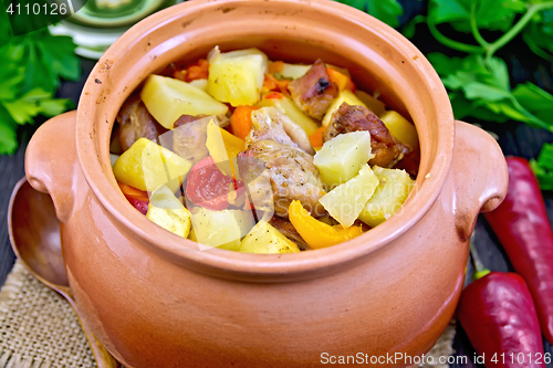 Image of Roast meat and vegetables in clay pot on burlap