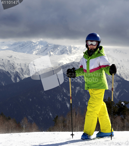 Image of Young skier with ski poles at sun mountains and cloudy gray sky