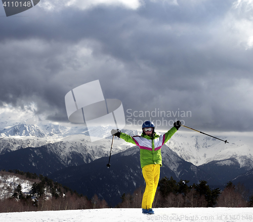 Image of Happy young skier with ski poles in sun mountains