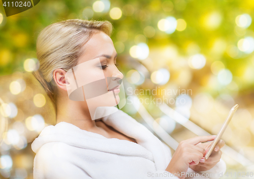 Image of beautiful young woman with smartphone at spa