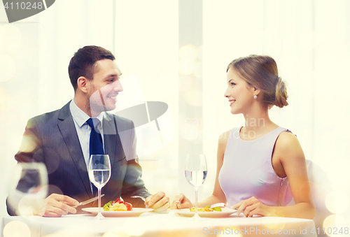 Image of smiling couple eating main course at restaurant