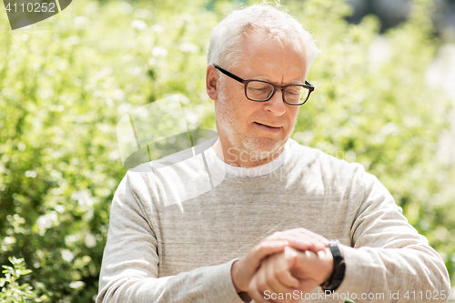 Image of senior man checking time on his wristwatch