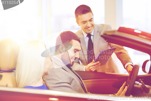 Image of happy couple with car dealer in auto show or salon