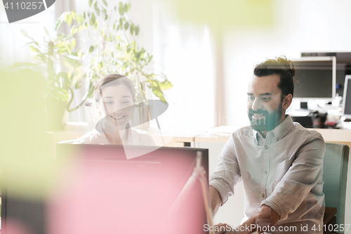 Image of happy creative team with computer in office