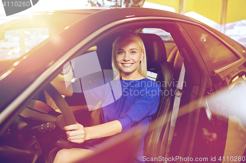 Image of happy woman inside car in auto show or salon