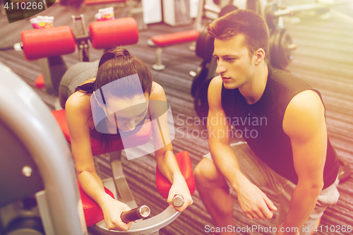 Image of young woman with trainer exercising on gym machine