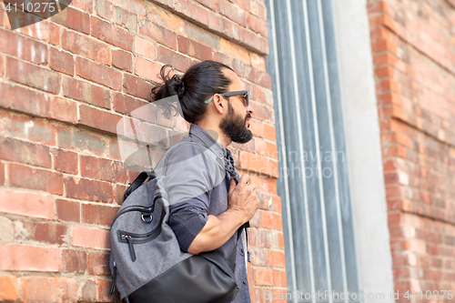 Image of man with backpack standing at city street wall