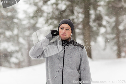 Image of sports man with earphones in winter forest