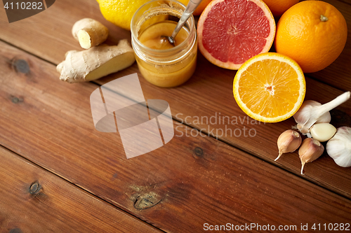 Image of honey, citrus fruits, ginger and garlic on wood