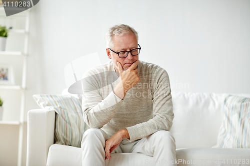 Image of  senior man sitting on sofa at home and thinking
