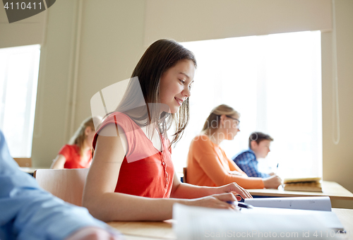 Image of happy student girl with book writing school test