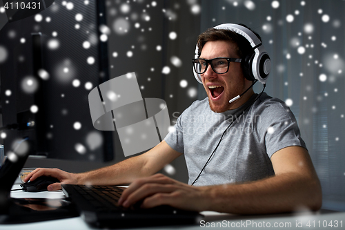 Image of man in headset playing computer video game at home