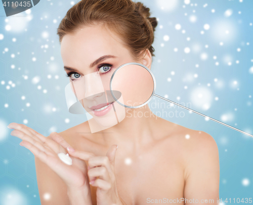 Image of happy young woman with moisturizing cream on hand