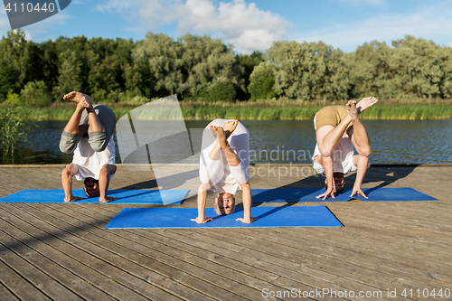 Image of people making yoga in crane pose outdoors