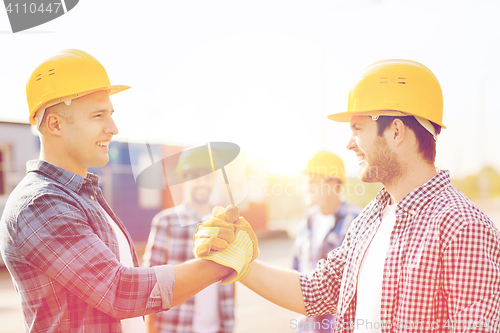 Image of group of smiling builders in hardhats outdoors