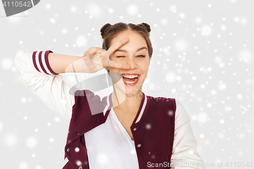 Image of happy teenage girl showing peace sign over snow