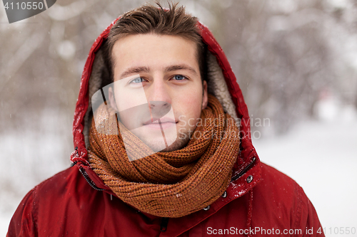 Image of happy man in winter jacket with hood outdoors