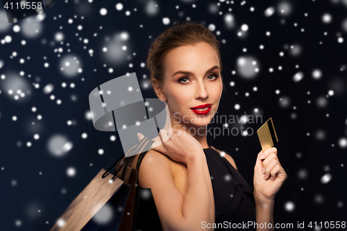 Image of woman with credit card and shopping bags over snow